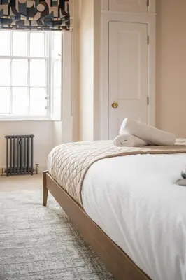 a bedroom with a bed with white sheets and a window at Stirling Townhouse Apartment Mid in Stirling