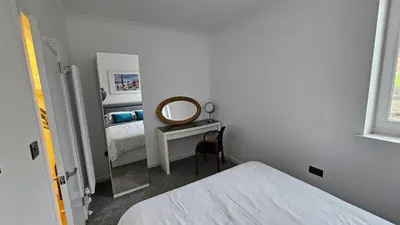 a white bedroom with a mirror and a bed at Harbour Havens Apartments in Moffat