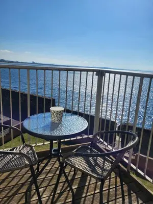 a table and chairs on a balcony overlooking the ocean at Harbour Point -Coorie Doon Stays in Saltcoats