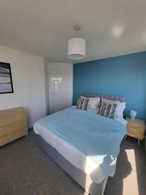 a bedroom with a large bed with a blue wall at Harbour Point -Coorie Doon Stays in Saltcoats