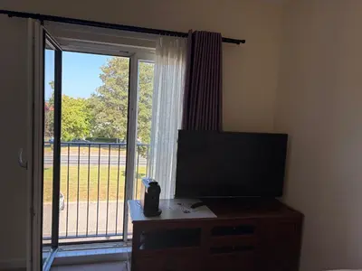 a room with a television and a sliding glass door at City Getaway - Homestay in Edinburgh