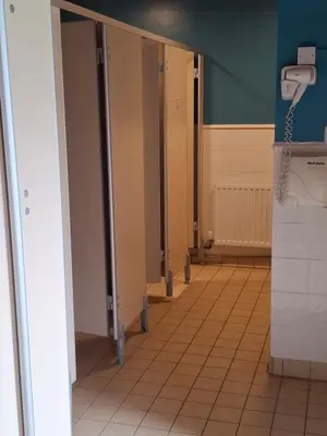 a row of stalls in a bathroom with a urinal at The Coo Shed 94 in Newton Stewart