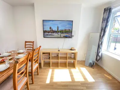 a dining room with a table and a tv on the wall at Luxurious 3 rooms greater London in Moffat