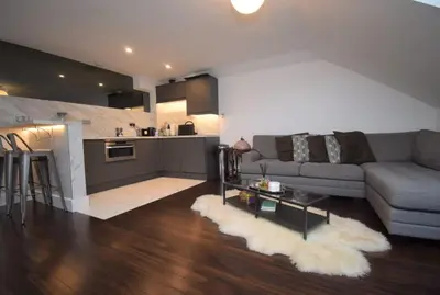 a living room with a couch and a table and a kitchen at Stylish Central Flat George Sq in Glasgow