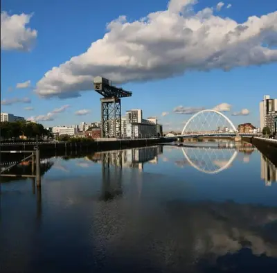 a bridge over a river with a city in the background at Stylish Central Flat George Sq in Glasgow