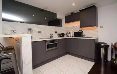 a kitchen with black cabinets and white tile floors at Stylish Central Flat George Sq in Glasgow
