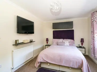 a bedroom with a bed and a flat screen tv at RoseGrace Lodge in Auchterarder