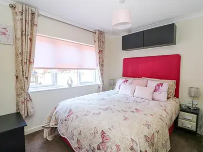 a bedroom with a large bed with a red headboard at RoseGrace Lodge in Auchterarder