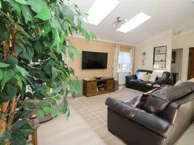 a living room with a couch and a large plant at RoseGrace Lodge in Auchterarder