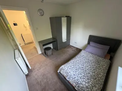 a bedroom with a bed and a table and a door at Cosy two bedroom flat in Glasgow