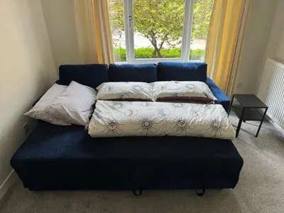 a blue couch with pillows on it in front of a window at Cosy two bedroom flat in Glasgow
