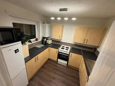 a kitchen with white cabinets and black counter tops at Cosy two bedroom flat in Glasgow