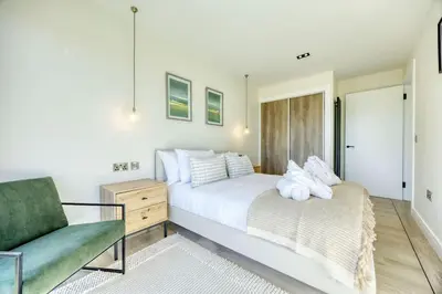 a bedroom with a white bed and a green chair at Retreat to the Campsies in Lennoxtown