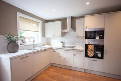 a kitchen with white cabinets and a sink and a window at Newly Renovated House in Popular Location in Glasgow