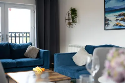 a living room with two blue couches and a table at Macallan Apartment in Oban