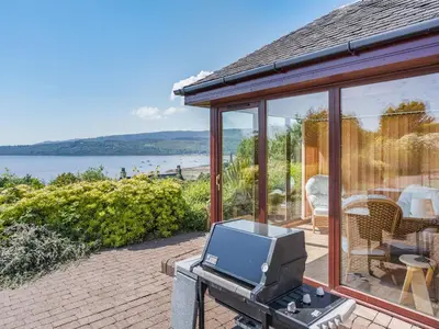 a house with a tv on a brick patio at Kilbride in Lamlash