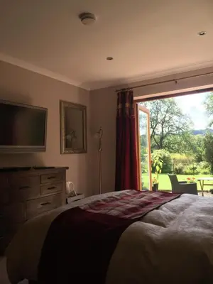 a bedroom with a bed and a tv and a window at Riverside House in Callander