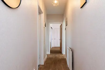 a hallway with white walls and wooden floors and a ceiling at 3Bedroom Apartment-Free Parking in Falkirk