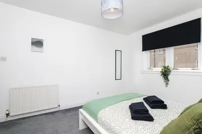 a white bedroom with a bed with towels on it at 3Bedroom Apartment-Free Parking in Falkirk