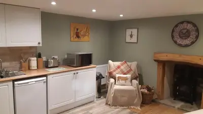 a kitchen with a counter and a chair and a clock at A Cozy Bothy Retreat with Hot Tub in Keilour