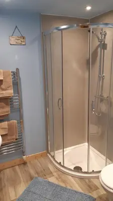 a shower with a glass door in a bathroom at A Cozy Bothy Retreat with Hot Tub in Keilour