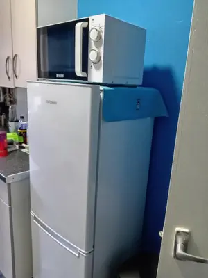 a microwave on top of a refrigerator in a kitchen at Pokój 1osobowy in Moffat
