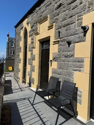 two chairs sitting in front of a brick building at Modern apartment in town centre in Oban