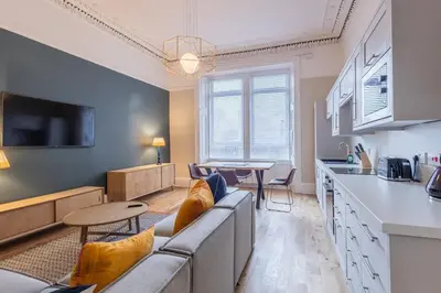 a living room with a couch and a table and a kitchen at 3BR Gem West End Walk to Glasgow Uni Parking in Glasgow