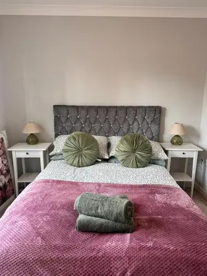 a bedroom with a bed with a purple blanket and pillows at 2BR Flat Free Parking Near Hampden and O2 Academy in Glasgow