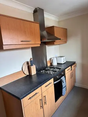 a kitchen with wooden cabinets and a stove top oven at 2BR Flat Free Parking Near Hampden and O2 Academy in Glasgow