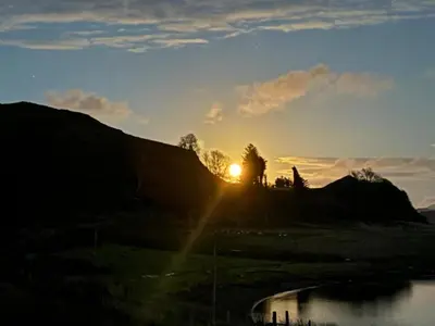 a sunset on a hill with the sun setting at Luxury Pod and Sauna with Fantastic Sea Views in Oban