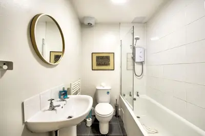 a bathroom with a sink and a toilet and a mirror at Grindlay St - Fantastic 2BR in Theatre District in Edinburgh