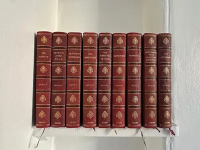 a row of red books sitting on a shelf at Grindlay St - Fantastic 2BR in Theatre District in Edinburgh