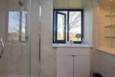 a bathroom with a shower and a sink and a window at Cliff Top - Bubbling Springs in Wemyss Bay