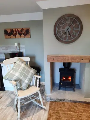 a room with a fireplace and a chair and a clock at A Stylish Country Retreat! in Keilour