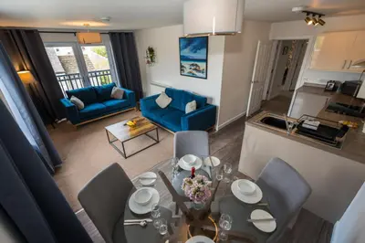 a dining room and living room with a table and chairs at Glenfiddich Apartment in Oban