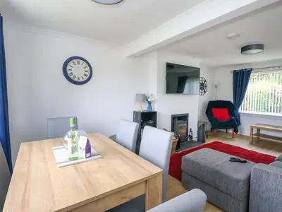 a dining room and living room with a table and a couch at 3 Whin Bank in Oban