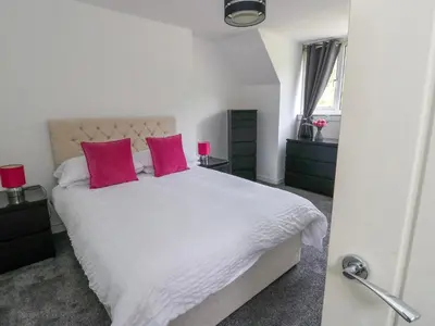 a bedroom with a white bed with two pink pillows at 3 Whin Bank in Oban