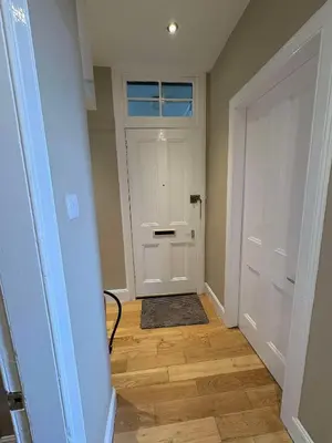 a hallway with a white door and a wooden floor at Central Oban 2BR Short walk to Ferries and Harbour in Oban