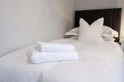 a pile of towels sitting on a white bed at Cottage in Crieff in Crieff