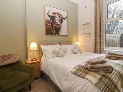 a bedroom with a bed and a chair and a window at 60E Wellgate in Lanark