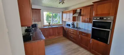 a kitchen with wooden cabinets and black appliances at Stylish Coastal Retreat in Saltcoats in Stevenston