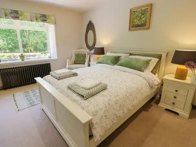 a bedroom with a bed and a mirror and a window at Nithbank Cottage in Thornhill