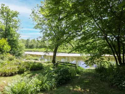 a park bench next to a lake with trees at Nithbank Cottage in Thornhill