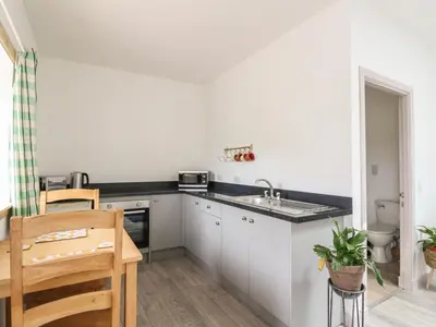 a kitchen with white cabinets and a sink and a table at Bathach Mor in Oban