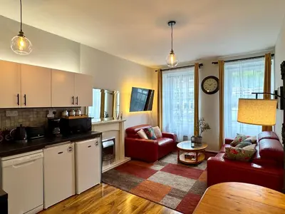 a kitchen and living room with a couch and a table at Stylish 2BR Grassmarket Flat with Castle Views & PS5 in Edinburgh