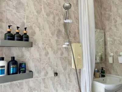 a shower in a bathroom with bottles of alcohol at Stylish 2BR Grassmarket Flat with Castle Views & PS5 in Edinburgh