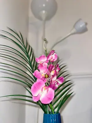 a blue vase filled with pink flowers next to a lamp at Luxury House in Glasgow in Mansewood