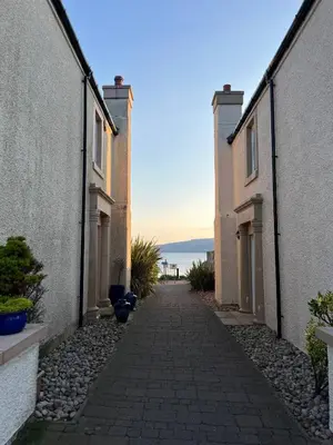 an alley between two buildings with the ocean in the background at Coastal Village Property in Inverkip