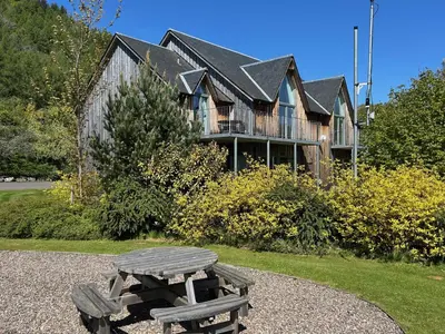 a wooden picnic table in front of a house at 6, The Gallops, Mains of Taymouth Estate, Kenmore in Kenmore